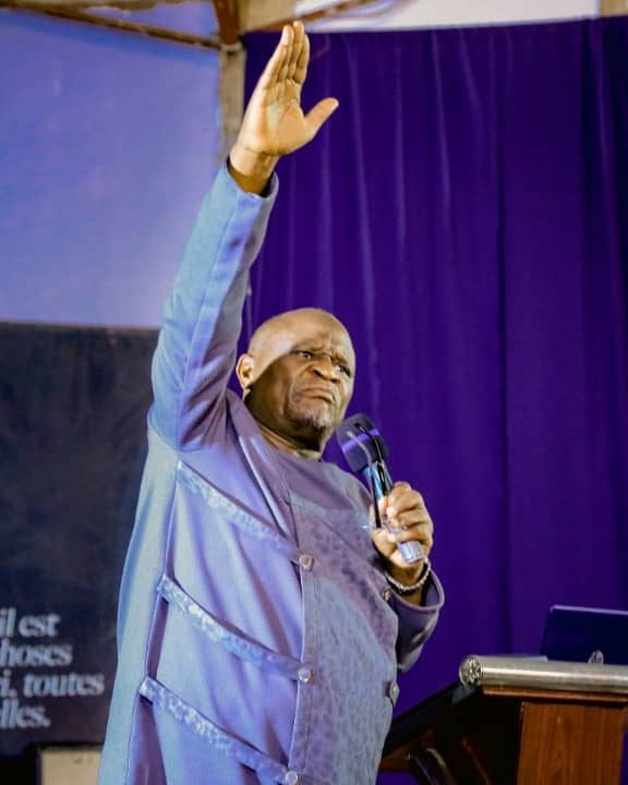 Apostle Dr. Felix Mukonowengwe ministering with a raised hand